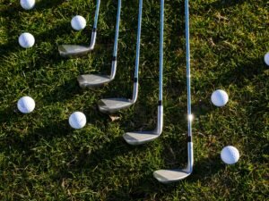 Welcome to Noble Fit Golf: My Must-Have Essentials for 2026 Flat lay of golf clubs and balls arranged on green grass, perfect for sports enthusiasts.