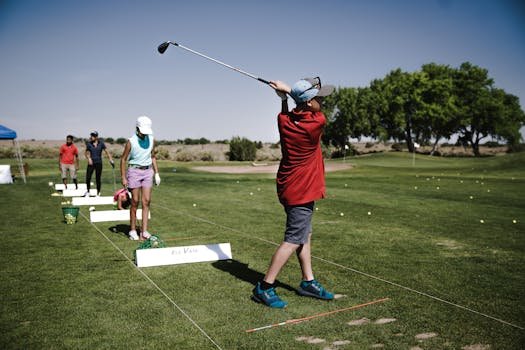 A group of youth practicing golf swings on a sunny day at the driving range.