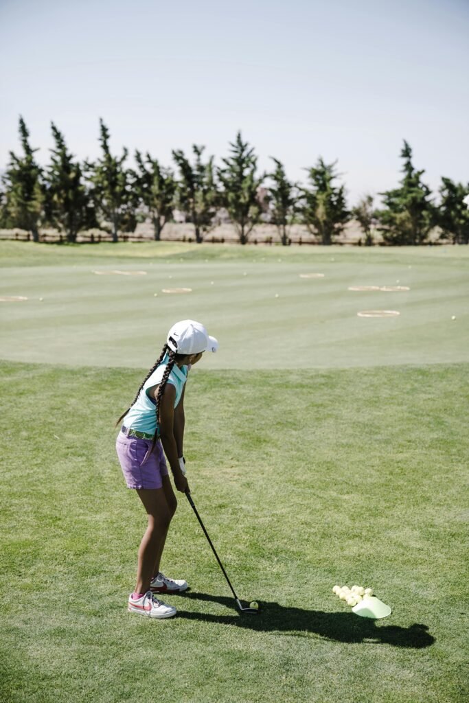 A child golfer prepares a swing on a sunny day on the golf course, showcasing youth sports.